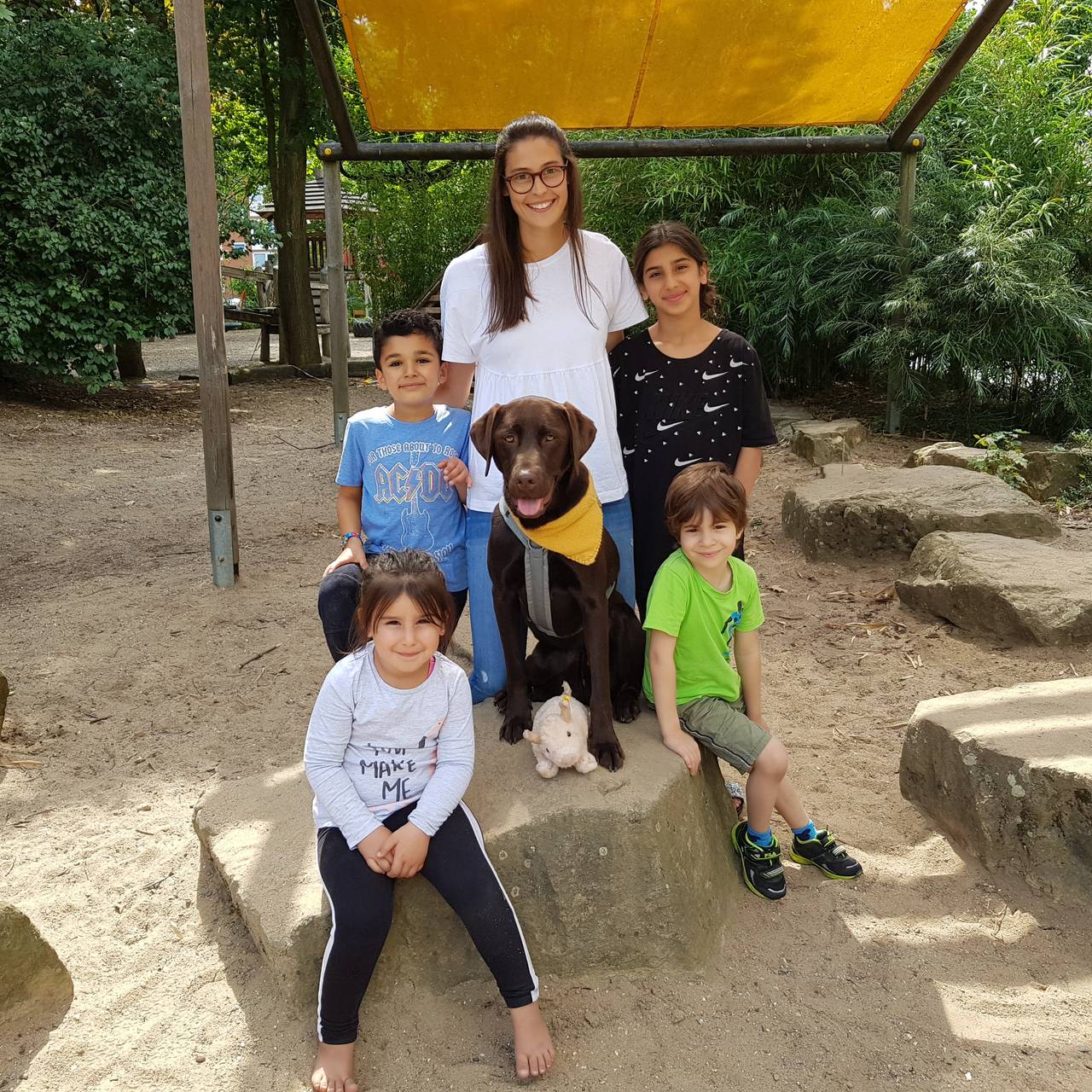 Kita-Hund Bruno ganz brav auf einem Stein zwischen Kindern