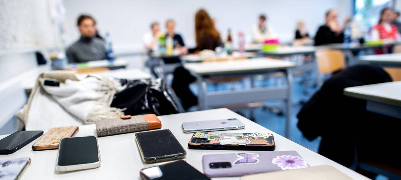 Zahlreiche Smartphones der Schülerinnen und Schüler liegen vor Beginn der schriftlichen Abiturprüfungen auf einem Tisch