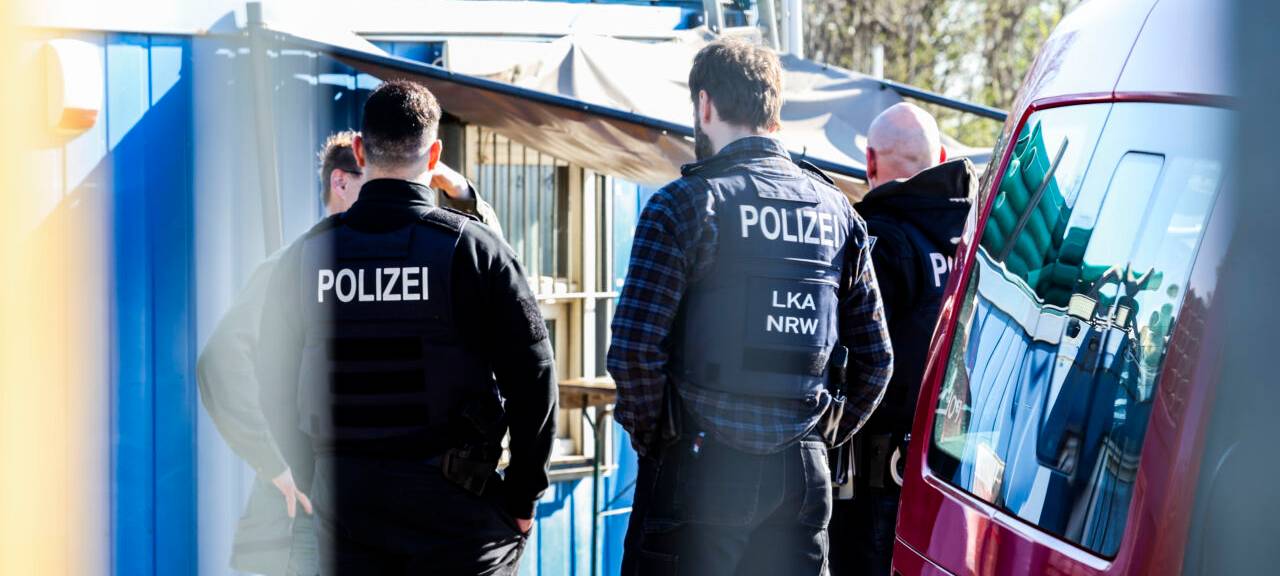 Polizeibeamte und LKA-Mitarbeiter stehen auf dem Betriebsgelände einer Kiesgrube.