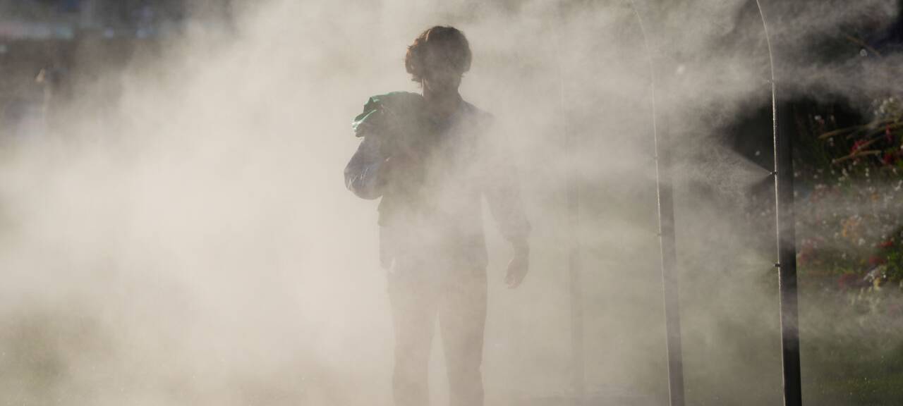Olympia, Paris 2024, eine Person geht durch einen Sprühnebel-Zerstäuber und kühlt sich ab.