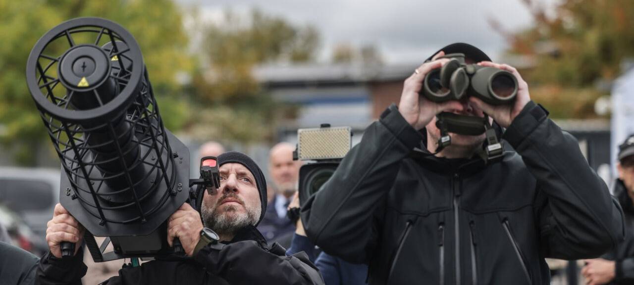 Polizisten der Drohnenabwehr peilen mit einem Jammer (l) und einem Fernglas (r) bei einer Vorführung eine Drohne an. Die Polizei in Nordrhein-Westfalen hat ihre Möglichkeiten zur Drohnenabwehr vorgestellt.