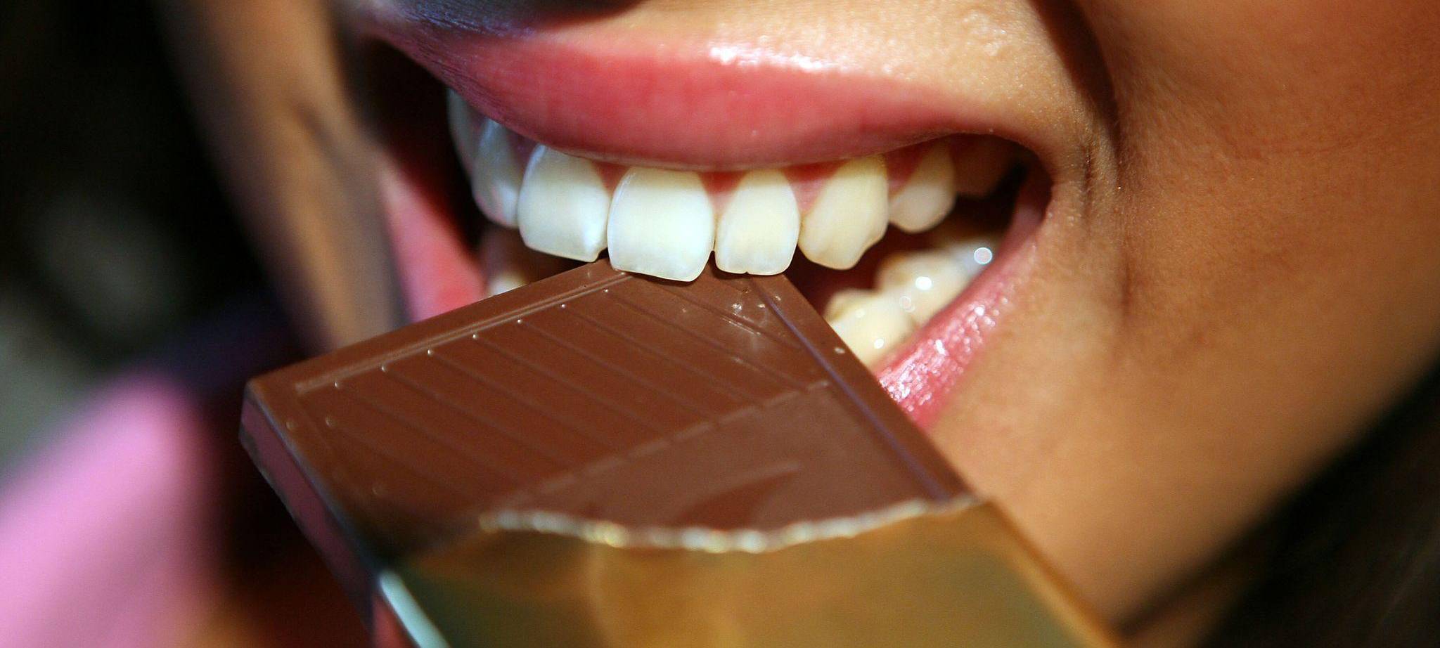 Frau beißt in eine Tafel Schokolade