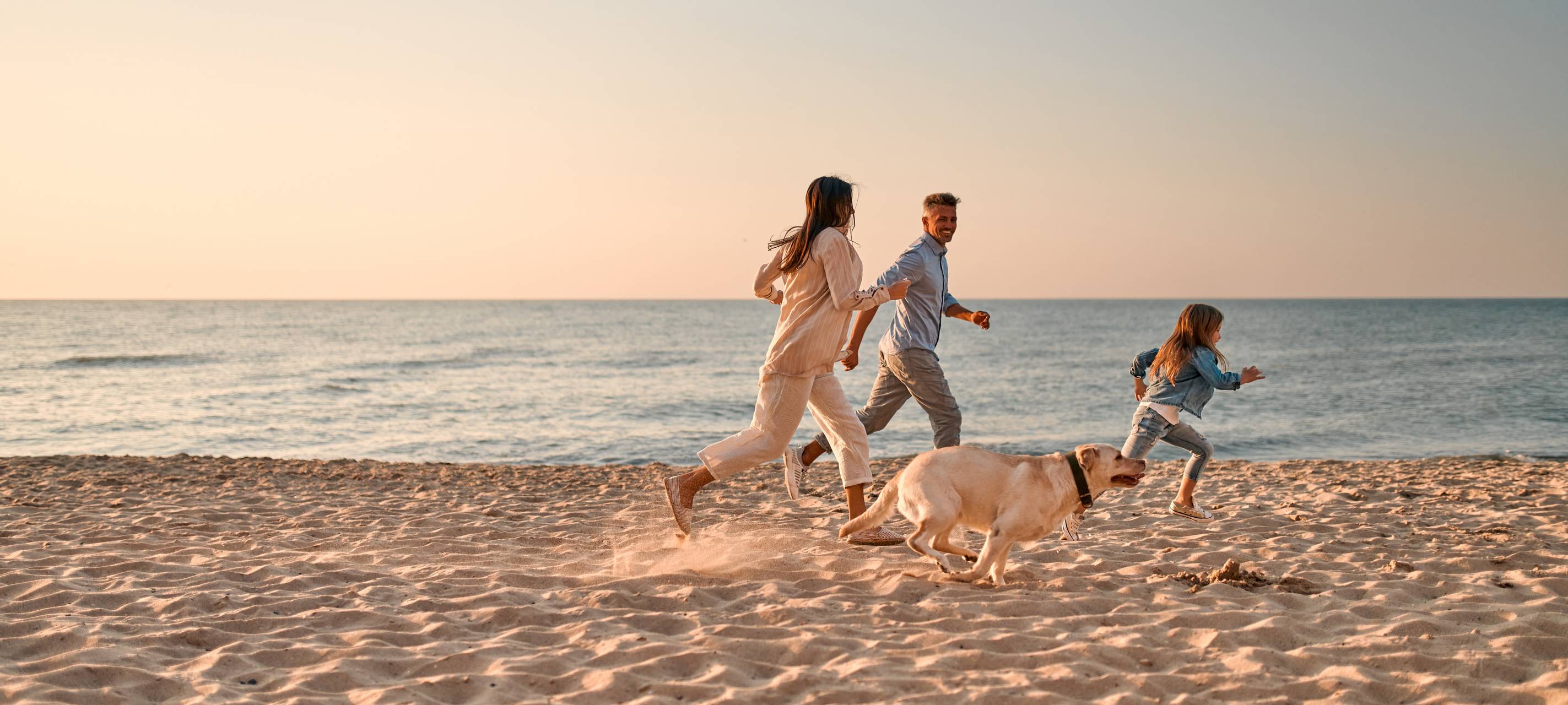Glückliche Familie mit Hund am Strand